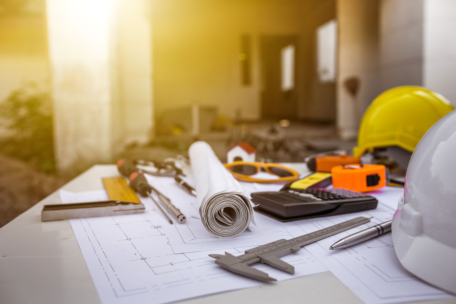 Engineering drawings, calipers and a safety helmet on a design desk